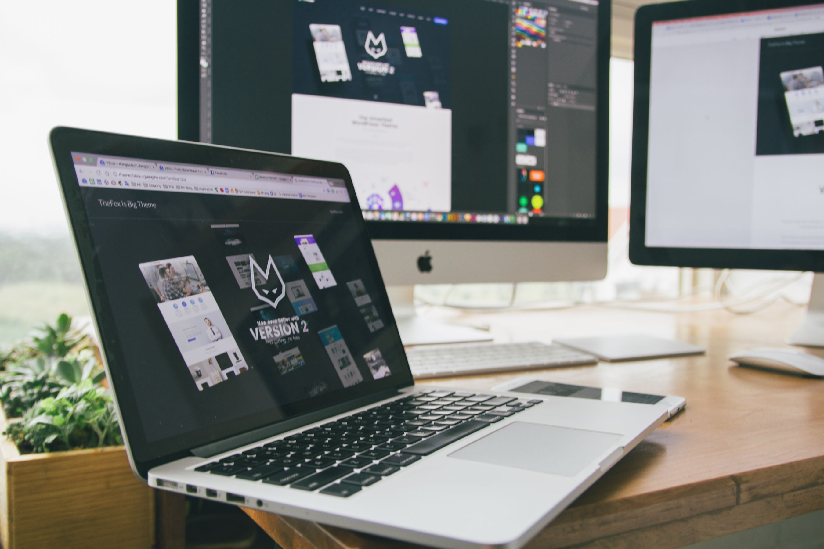 Laptop showing website design tools on a desk